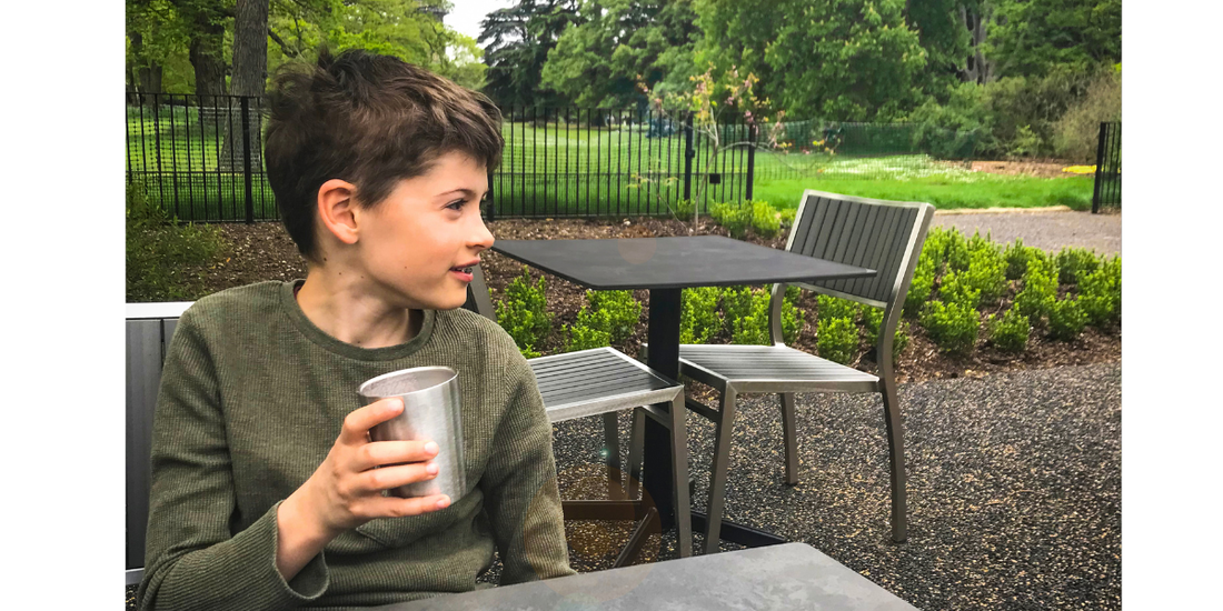 Kind hält KiNDKiT Edelstahl Becher im Park nachhaltig BPA-frei
